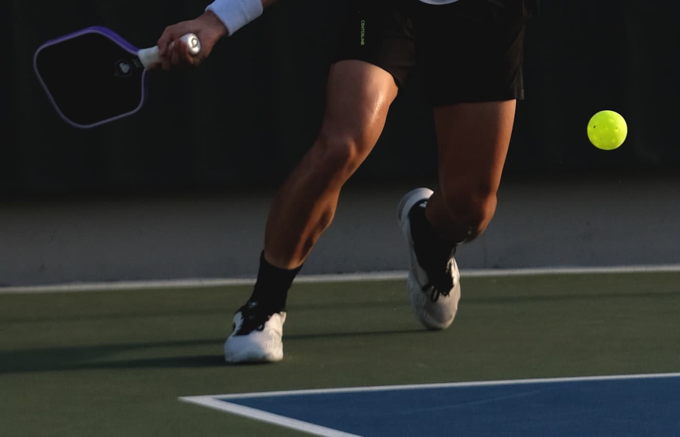 Player at the non-volley zone line preparing to hit a soft pickleball shot