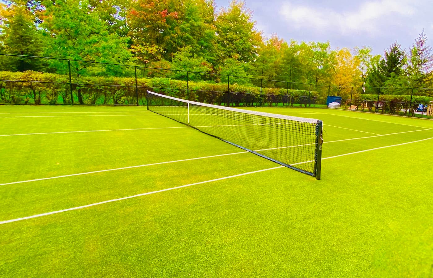 Outdoor pickleball courts under cloudy UK sky with players mid-rally