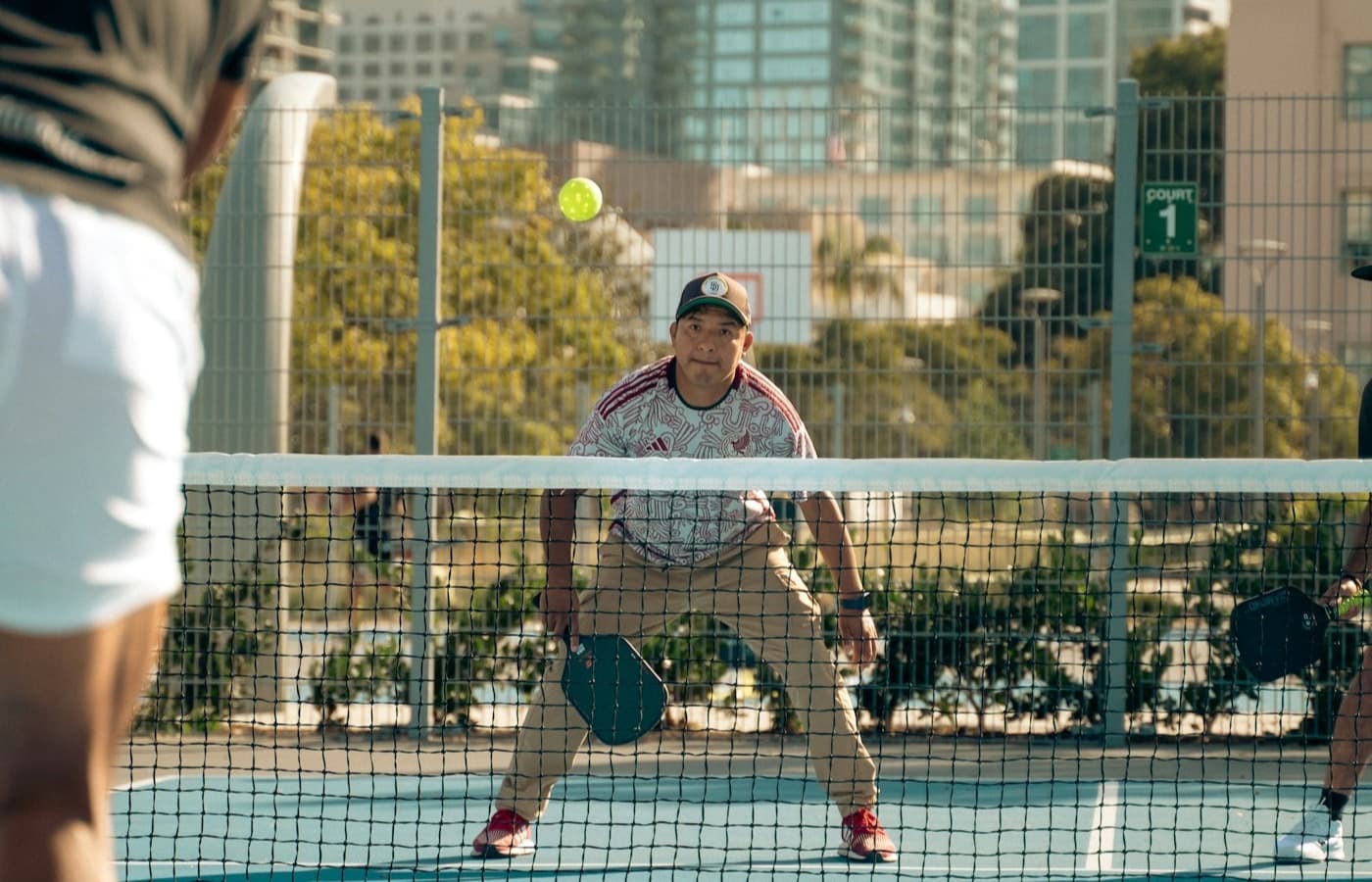 Players contesting a pickleball rally on an outdoor club court