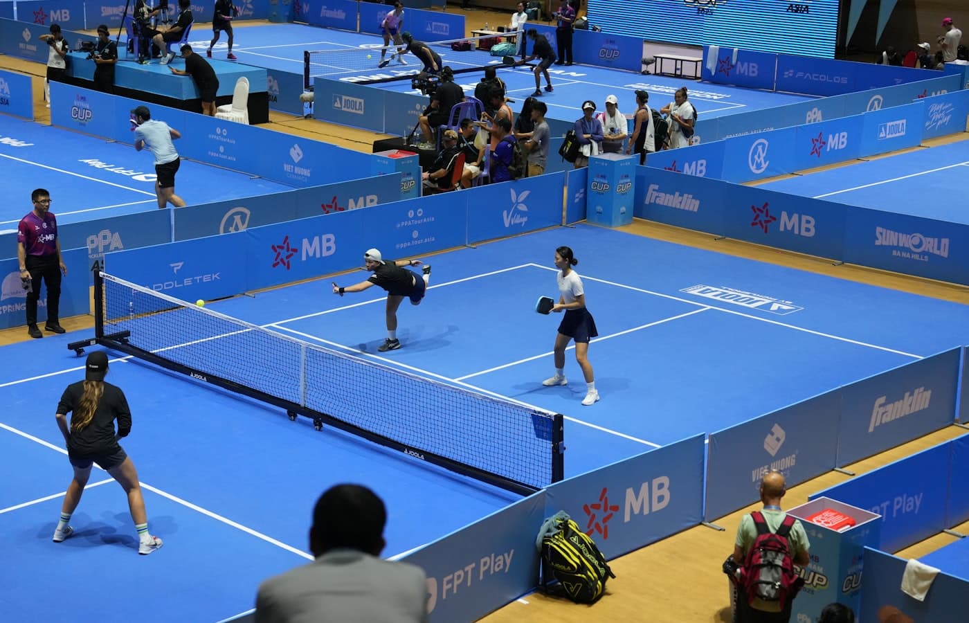 Two pickleball players at the baseline about to start a game on an indoor court